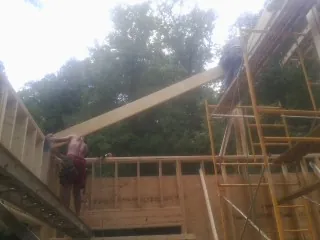 Carpenter raising a rafter beam on a new second story frame in Groveland