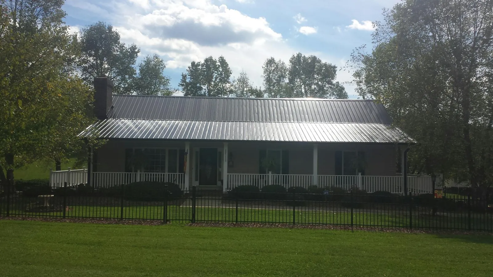 Gray metal roof on a brick ranch with a full width front porch — Gutter Guard Installation work by our crew in Groveland