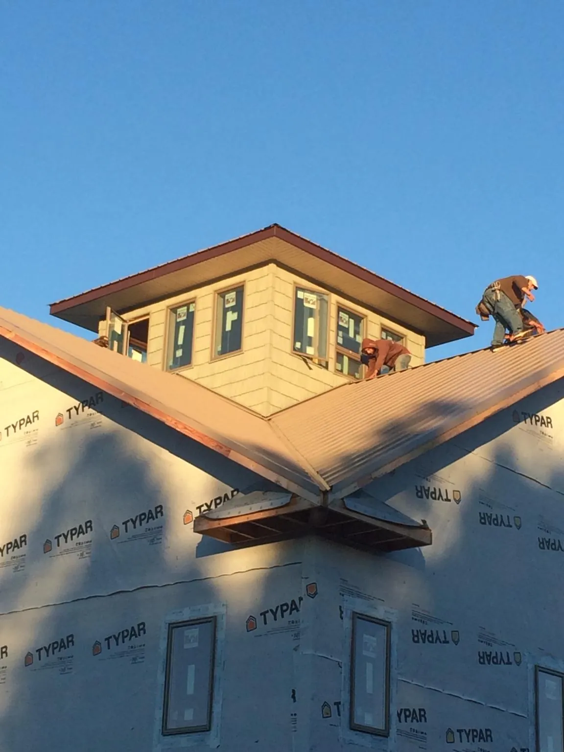 Roofers working around a rooftop cupola on a new metal roof at sunset — Roof Waterproofing in Groveland by Roofing Brothers